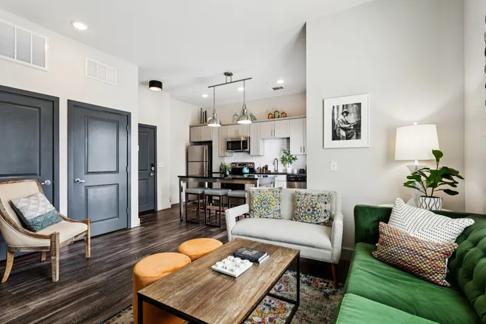 Contemporary apartment living room with stylish decor, featuring a cozy sofa, vibrant cushions, and a sleek open-concept kitchen.