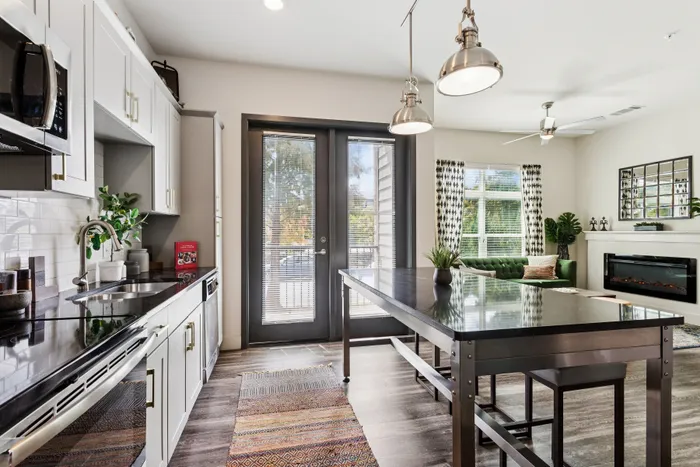 Bright modern kitchen and living area with sleek appliances, cozy green sofa, and stylish decor.