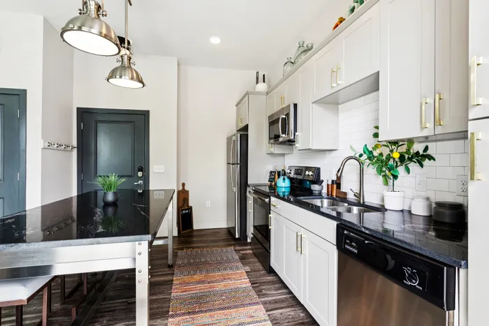 Modern kitchen featuring sleek white cabinetry, stainless steel appliances, and elegant pendant lighting.