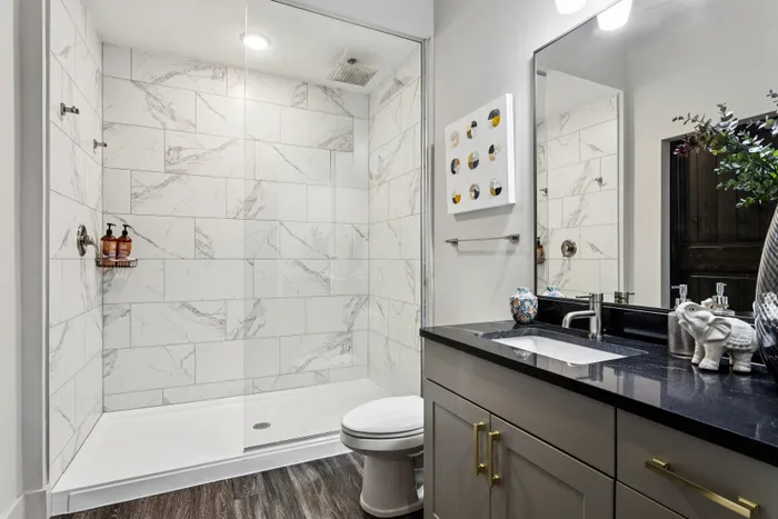Luxurious bathroom with elegant marble-tiled shower, sleek black countertop, and stylish decor for a modern touch.