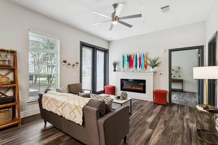 Elegant living room featuring modern decor, cozy sofa, vibrant artwork, and sleek fireplace with natural light streaming through large windows.