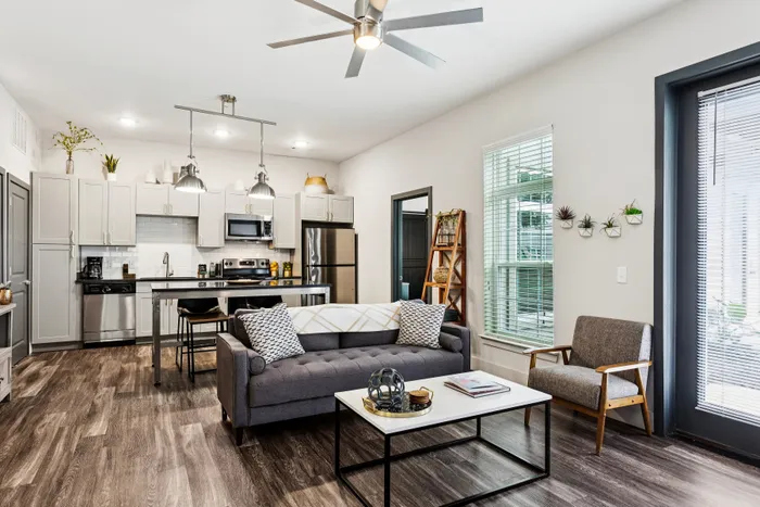 Modern and inviting open-concept kitchen and living room with sleek finishes, featuring a stylish sofa, elegant dining area, and abundant natural light.