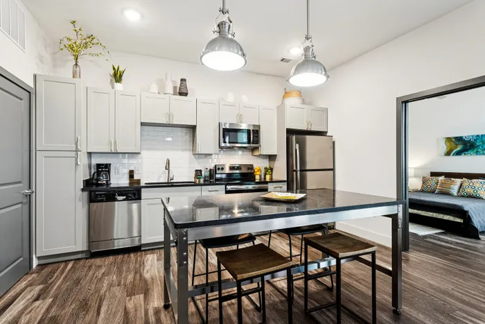 Modern kitchen with sleek stainless steel appliances, elegant cabinetry, and a spacious dining island, seamlessly leading into a cozy bedroom.