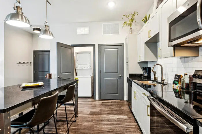 Modern kitchen with sleek appliances, stylish cabinetry, and a convenient in-unit laundry area, ideal for contemporary living.