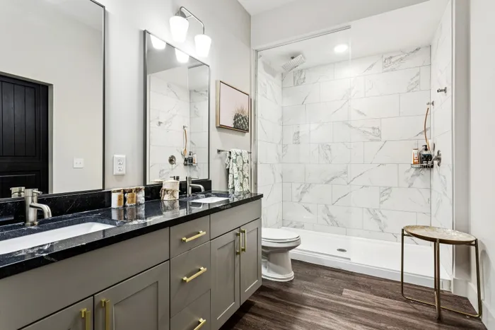 Luxurious bathroom with elegant marble-tiled shower, sleek dual sinks, and sophisticated lighting.