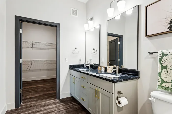 Modern bathroom with dual sinks, elegant lighting, and spacious walk-in closet.