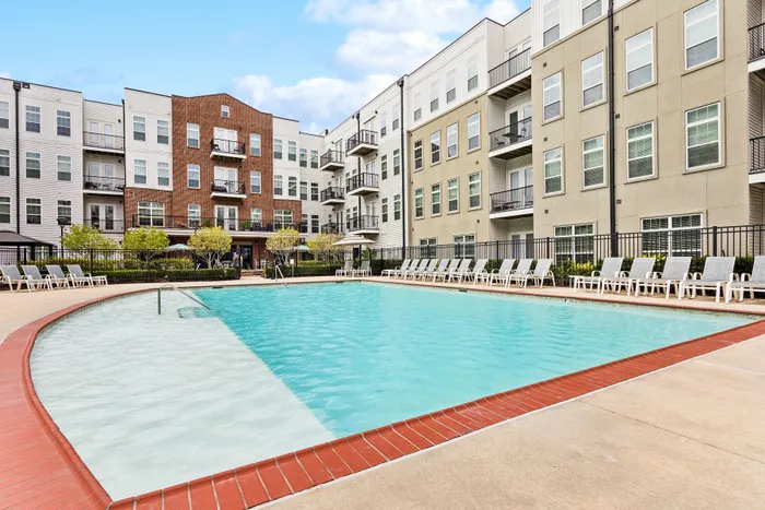 Luxurious apartment complex showcasing a stunning outdoor pool area surrounded by contemporary multi-story buildings and stylish lounge chairs.