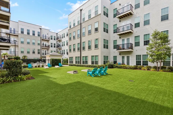 Inviting apartment courtyard featuring lush green lawn, modern seating, and charming balconies, perfect for relaxation and leisure.