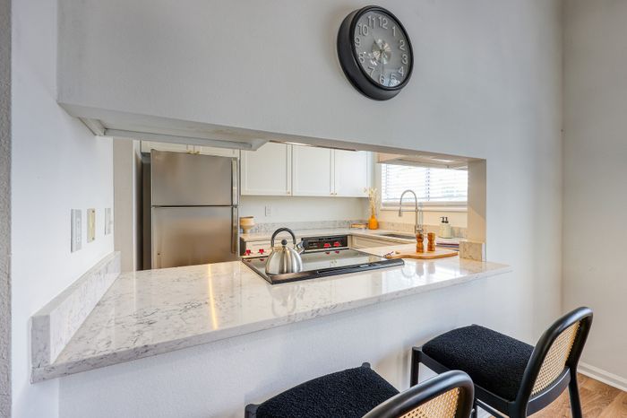Modern kitchen with sleek countertops, stainless steel appliances, and chic bar seating inviting a cozy culinary experience.