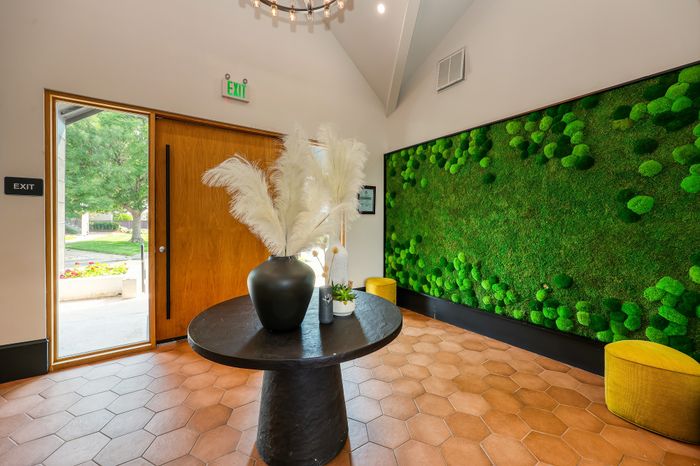Inviting entrance with a chic round table, elegant vase, and captivating green moss wall art, creating a welcoming and stylish atmosphere.