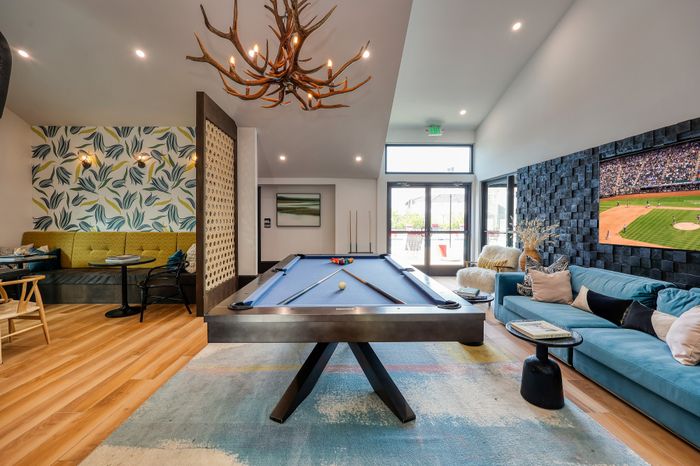 Vibrant entertainment room featuring a sleek pool table, cozy seating area with patterned wallpaper, and a large TV screen for ultimate relaxation.