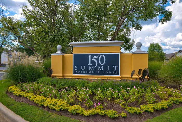 Charming entrance sign for 150 Summit Apartment Homes, surrounded by lush greenery and vibrant flowers, showcasing a welcoming community atmosphere.