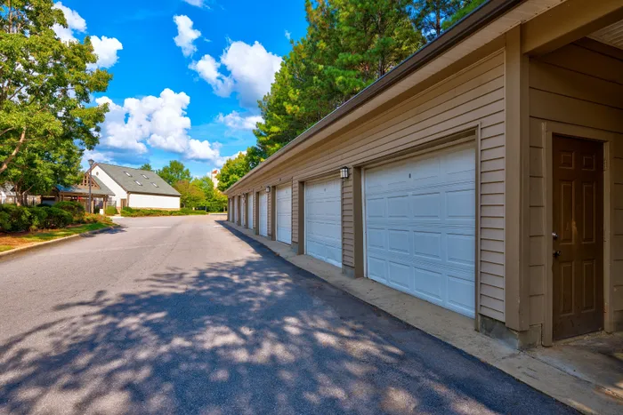 Charming residential community with private garages and lush greenery under a vibrant blue sky.