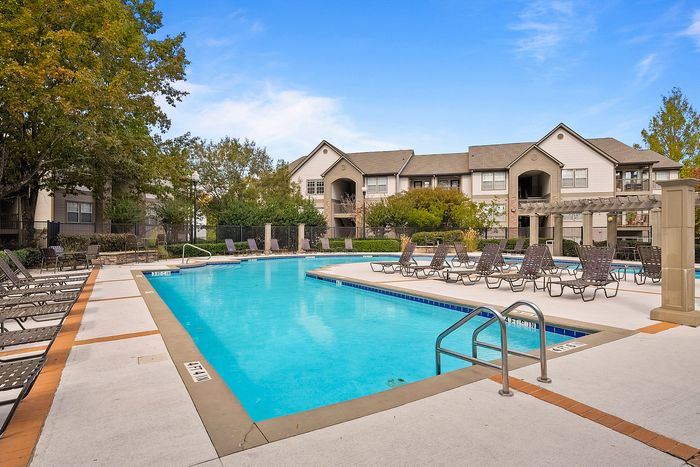 Inviting outdoor pool area surrounded by lush greenery and elegant apartment buildings, ideal for relaxation and leisure.