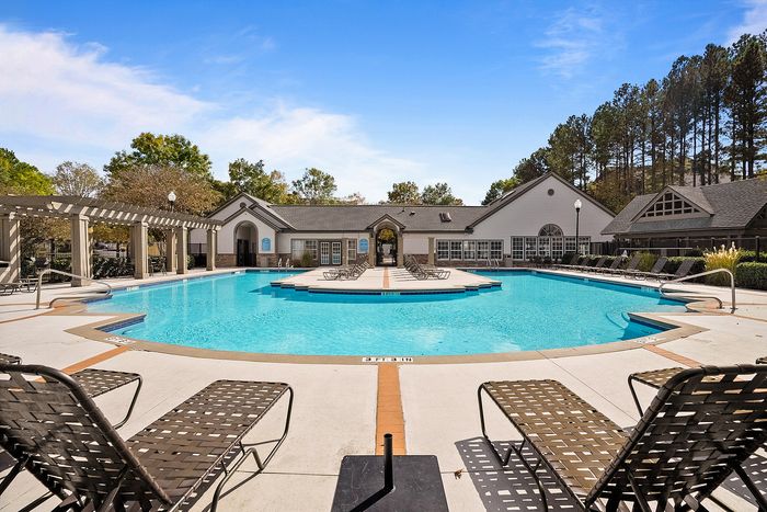 Luxurious apartment complex pool area with elegant sun loungers, scenic views, and beautifully maintained landscape.