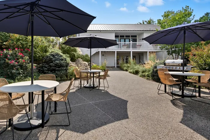Charming outdoor patio with modern furniture, large umbrellas, and lush greenery perfect for relaxation and entertainment.
