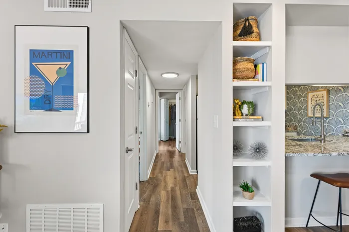 Modern hallway with elegant wooden flooring, a chic framed art piece, and stylish built-in shelving adding a touch of sophistication.