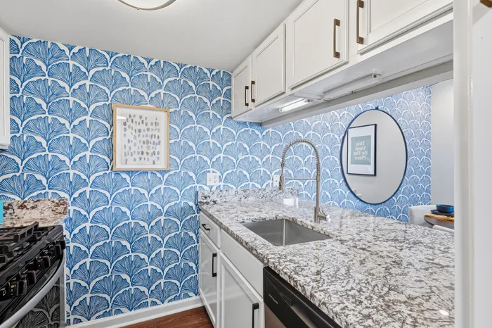 Chic kitchen with elegant marble countertops, bold blue patterned wallpaper, and contemporary fixtures for a stylish look.