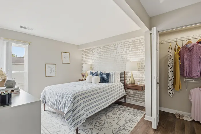 Bright and modern bedroom with elegant decor, spacious walk-in closet, and large window for natural light.