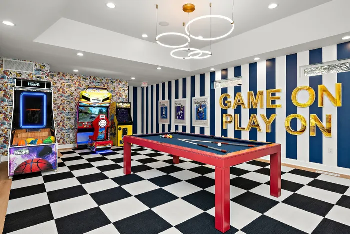 Vibrant game room featuring a modern pool table, classic arcade machines, and playful decor with bold stripes and lively graphics, perfect for entertainment and fun.