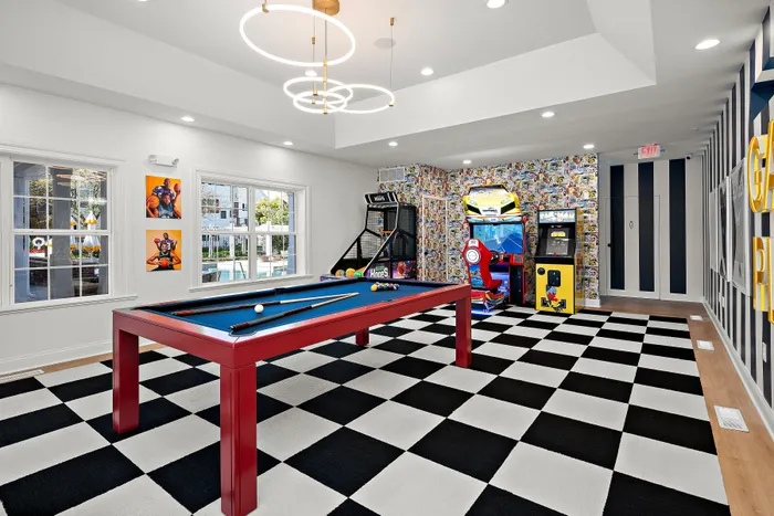 Vibrant game room featuring a modern pool table, arcade games, and stylish checkered flooring.