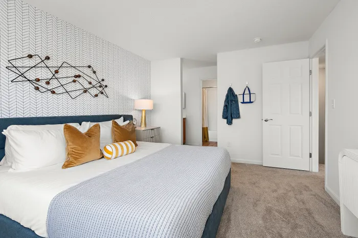 Chic bedroom with modern decor featuring a plush bed with stylish pillows, textured wallpaper, and a cozy atmosphere.