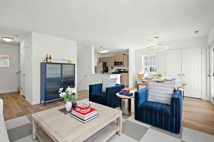Bright and inviting open-concept living area featuring modern kitchen, stylish velvet chairs, and cozy dining space with natural light.