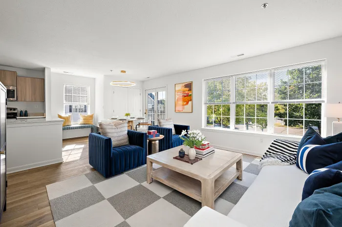 Bright and elegant living room with large windows, plush seating, and a cozy dining nook.