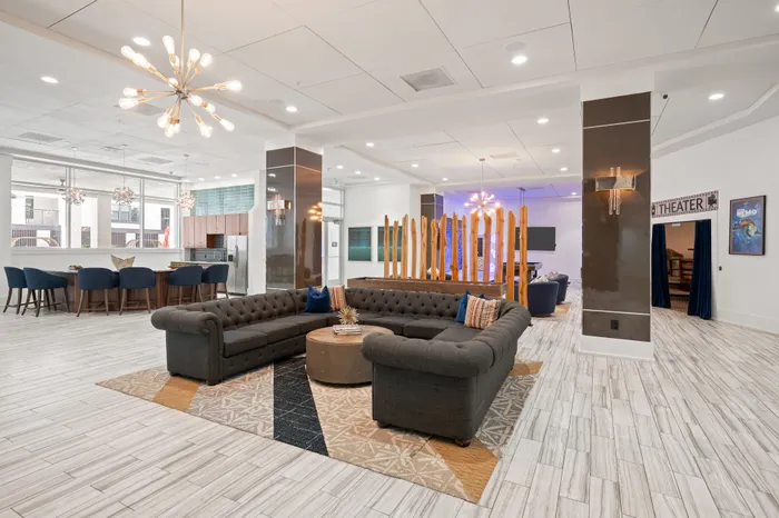 Elegant modern lobby with stylish sectional sofas, chic lighting fixtures, and an inviting dining area, perfect for gatherings and relaxation.