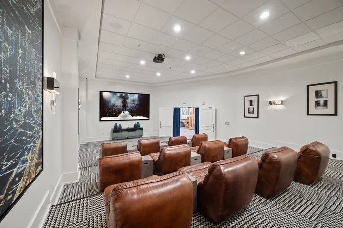 Luxurious apartment cinema room with leather recliners, large screen, and stylish decor.