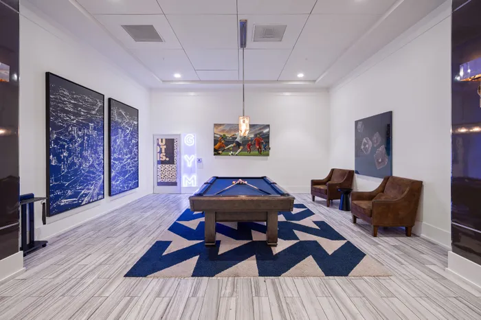 Chic game room featuring a sleek pool table, modern art, and comfortable seating on stylish flooring.