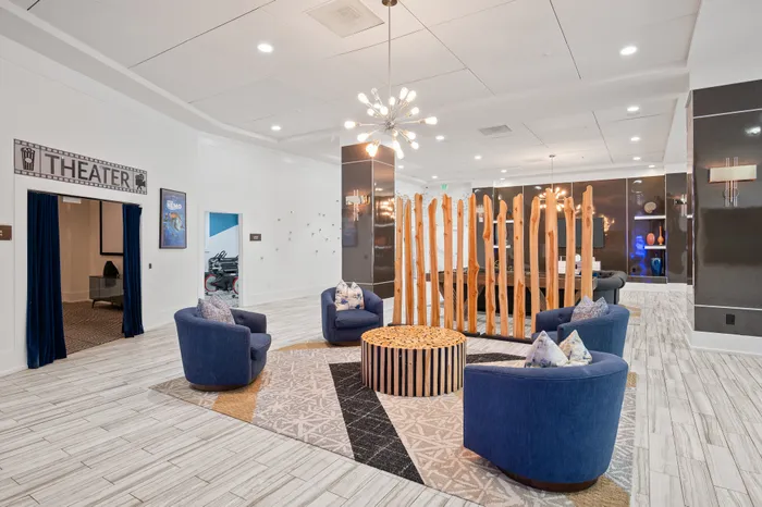 Elegant communal lounge area with stylish blue seating, modern lighting, and a theater room entrance.