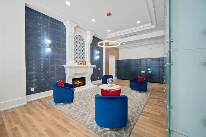 Chic apartment lobby with modern fireplace, plush blue chairs, and elegant lighting accents.
