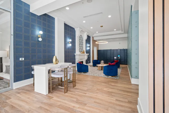 Elegant lobby area with luxurious blue seating, stylish decor, and a modern lighting fixture, perfect for relaxation or social gatherings.