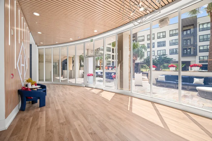 Bright and elegant lobby with floor-to-ceiling windows, stylish wood ceiling, and inviting seating area with vibrant outdoor views.