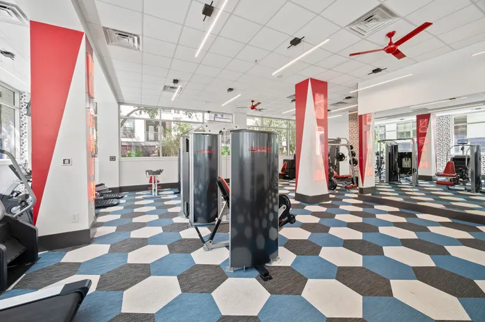Modern fitness center with vibrant design, featuring state-of-the-art equipment, sleek mirrors, and stylish patterned flooring.