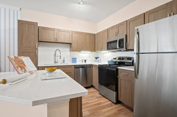 Modern kitchen with stainless steel appliances, elegant wooden cabinetry, and a sleek quartz countertop ideal for culinary adventures.