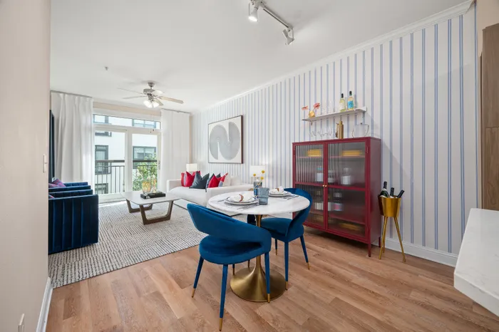 Elegant living area with chic blue armchairs, a cozy white couch, and tasteful modern decor under ample natural light from a large window.