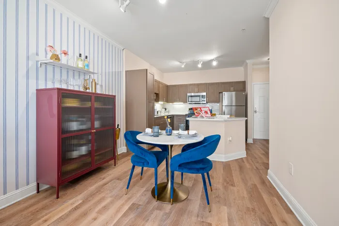 Chic dining area with vibrant blue chairs and a stylish kitchen featuring modern stainless steel appliances.