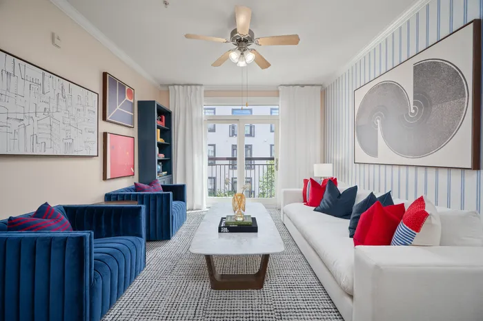 Chic and modern living room with vibrant blue couches, elegant artwork, and ample natural light through large windows.