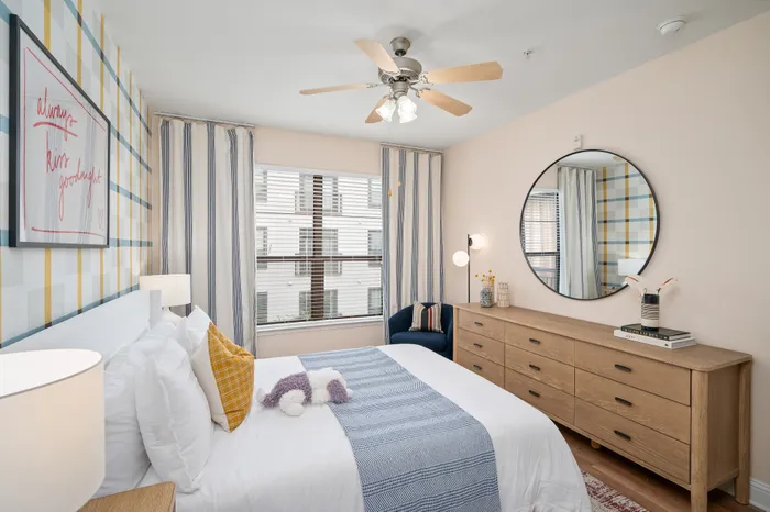 Inviting bedroom with plush bedding, striped curtains, and chic wall art, offering a serene retreat.