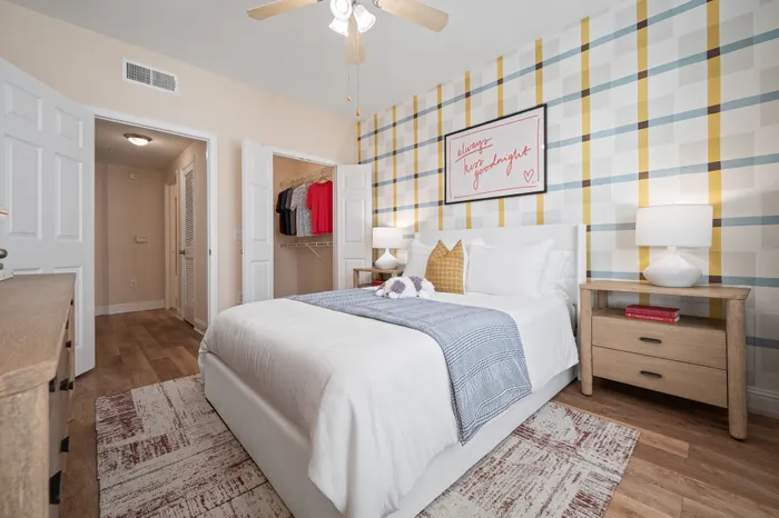 Inviting bedroom with a cozy queen-size bed, stylish plaid accent wall, and elegant wooden furnishings, perfect for a restful retreat.