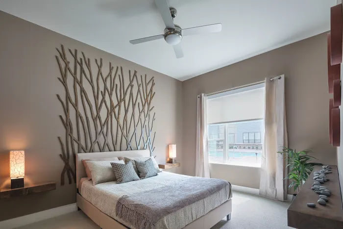 Elegant bedroom with nature-inspired wall decor, cozy bedding, and ample natural light from a large window with modern curtains.