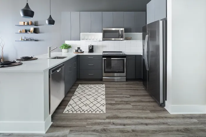 Modern kitchen with sleek gray cabinetry, stainless steel appliances, and stylish pendant lighting over a spacious countertop.