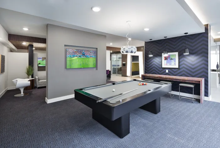 Modern game room featuring a sleek pool table, stylish lounge seating, and a vibrant wall design, perfect for entertainment and relaxation.