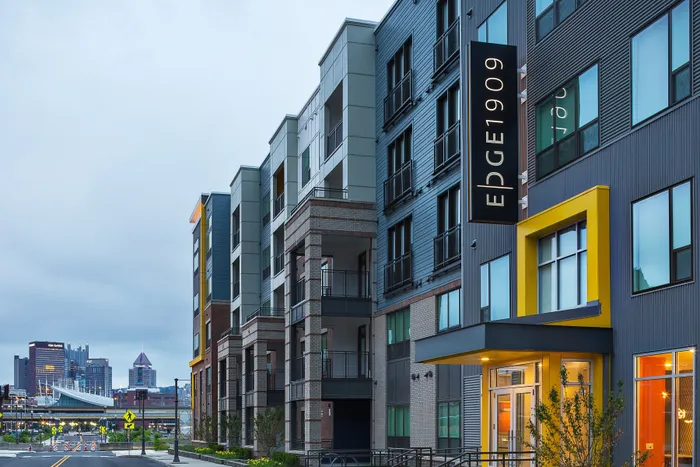 Modern apartment building with sleek architectural design, vibrant facade, and urban cityscape backdrop.