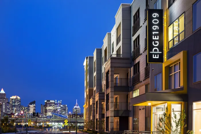 Modern urban apartment complex with stylish exterior and vibrant city skyline views at dusk.
