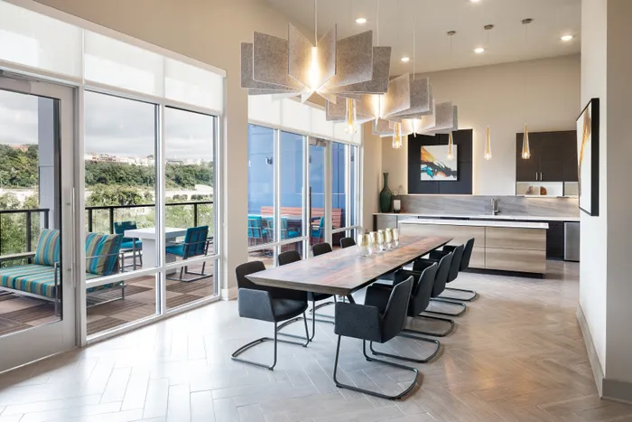 Luxurious open-concept dining area with modern lighting, elegant wooden table, and stylish chairs, opening to a scenic balcony view.