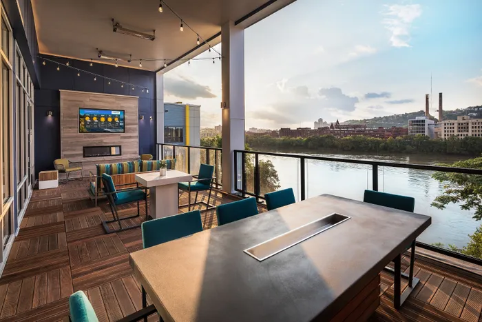Luxurious outdoor terrace featuring stylish seating, elegant dining table, and stunning river view at sunset.