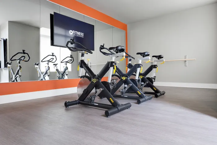 Modern fitness room showcasing sleek spin bikes, wall mirrors, and a vibrant orange accent, ideal for an invigorating workout experience.